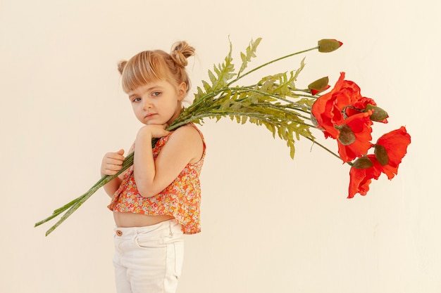 Бесплатное фото Маленькая девочка позирует с цветами