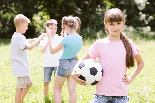 Маленькая девочка позирует с футбольным мячом