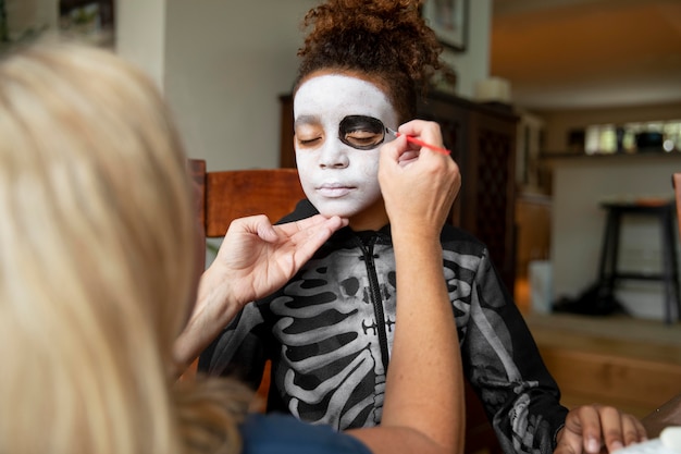 Bambina che si prepara per halloween con un costume da scheletro