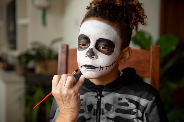 Маленькая девочка готовится к хэллоуину с костюмом скелета