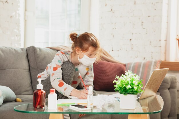 코로나 바이러스와 함께 집에서 격리 보호 마스크에 어린 소녀