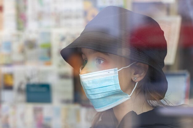 Little girl in a protective medical mask in a bookstore