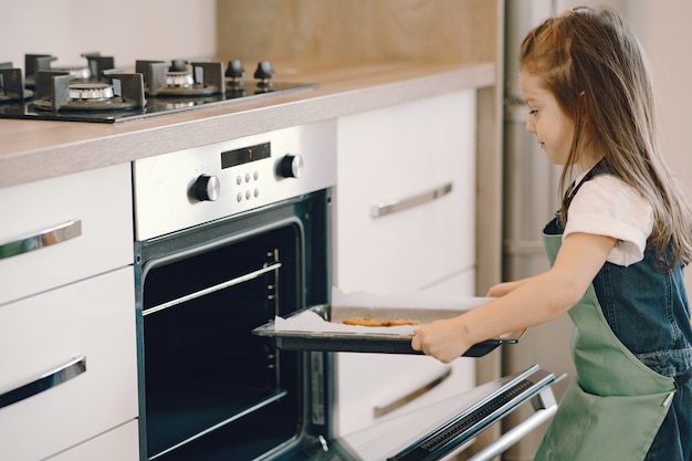 Free photo little girl pulls a cookie tray from the oven