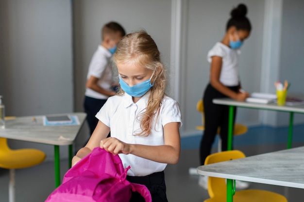 Little girl putting her books in her backpack