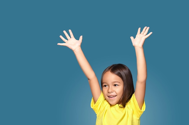 Free photo little girl raising her hands up. on blue background