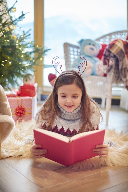 Little girl reading book on the floor