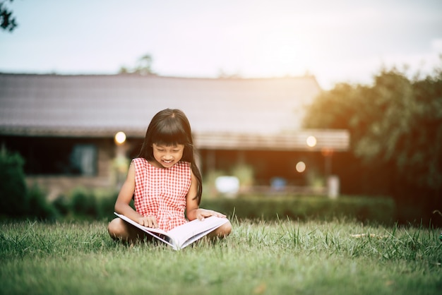 Little girl reading a book in the house garden