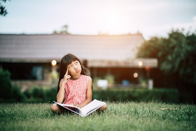 家の庭で本を読んでいる少女