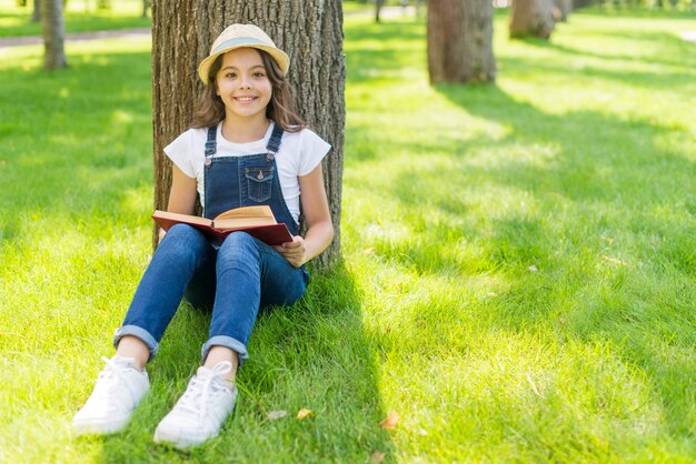 草の上に座って本を読む小さな女の子