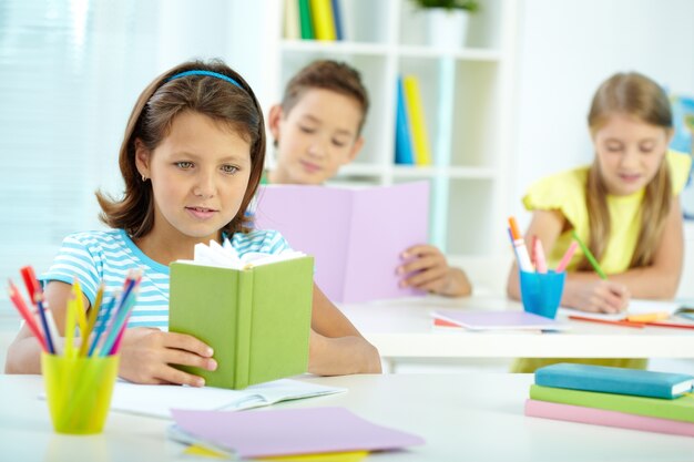 Little girl reading a green book