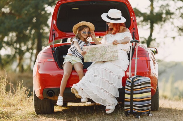 Little girl ready to go on vacations. Mother with daughter examining a map. Traveling by car with kids.