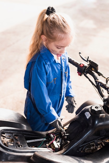 Бесплатное фото Маленькая девочка ремонтирует велосипед с помощью гаечного ключа