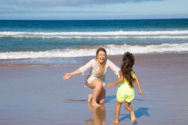 Little girl running into her happy moms open arms