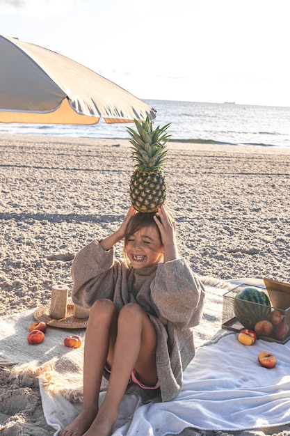 과일과 함께 피크닉에서 모래 해변에 어린 소녀