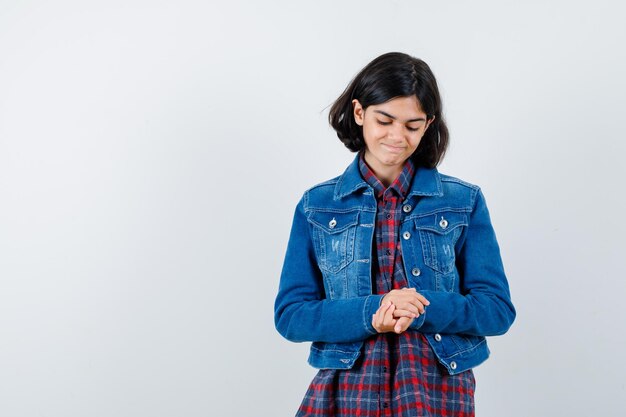 Little girl in shirt, jacket holding hands clasped and looking dreamy , front view.