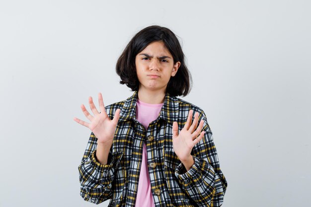 Little girl in shirt,jacket showing rejection gesture and looking reluctant , front view.