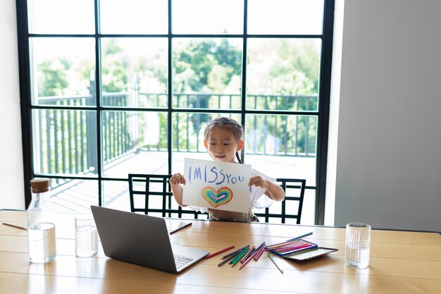 Little girl showing a drawing to a member of her family on a video call