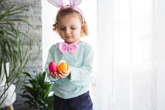 Foto gratuita bambina che mostra le uova di pasqua