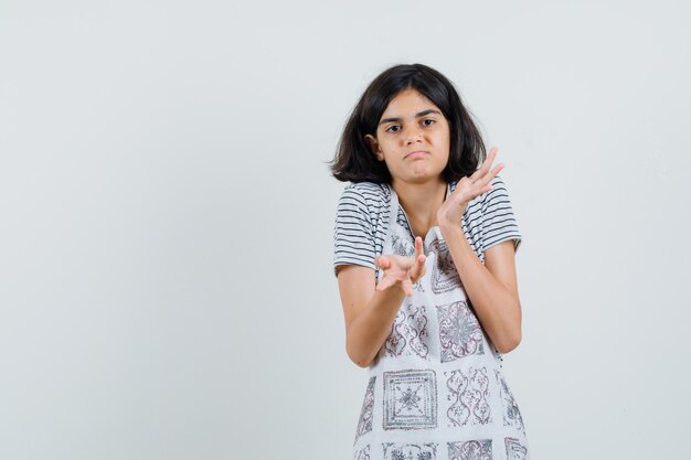 Tシャツ、エプロンで無力なジェスチャーを示し、混乱しているように見える少女