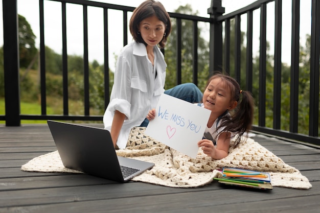 Free photo little girl showing an i miss you message for her dad on a video call