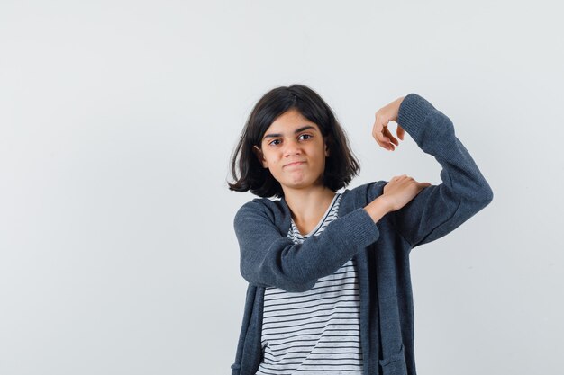 T- 셔츠, 재킷에 팔의 근육을 보여주는 자신감을 찾고 어린 소녀.