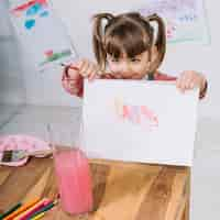 Free photo little girl showing painting on paper