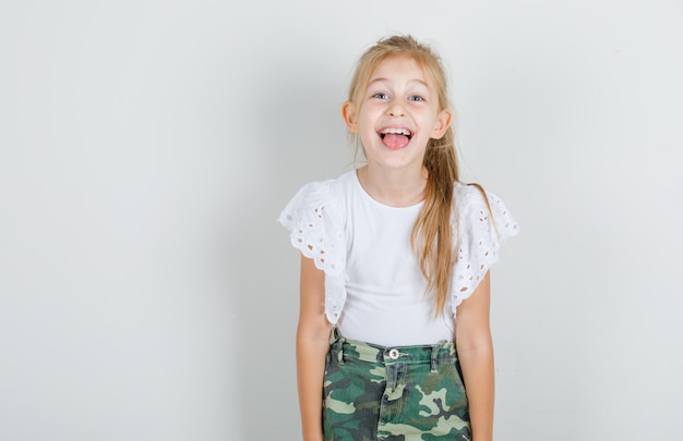 Бесплатное фото Маленькая девочка показывает язык в белой футболке