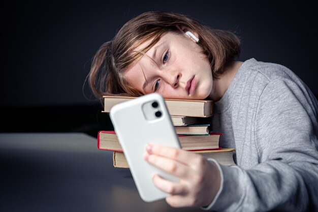 A little girl sits near books and takes a selfie bored from reading