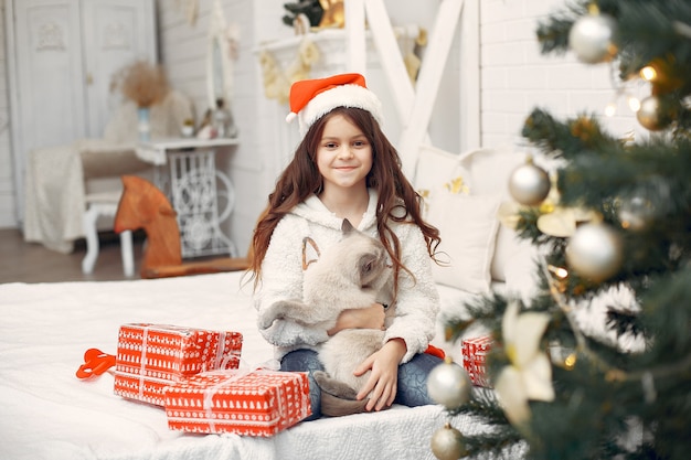 Free photo little girl sitting on a bed with cute kitty