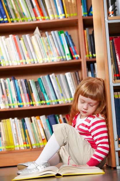 Little girl sitting on floor and reading book