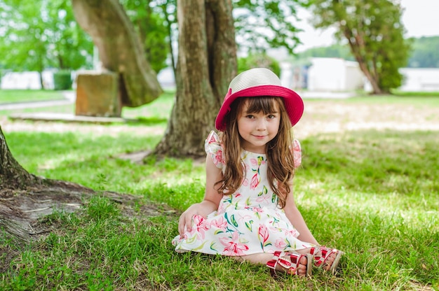 Bambina seduta sul pavimento con un cappello