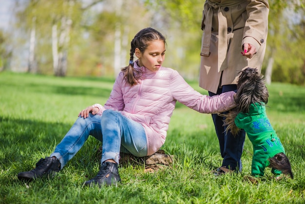 Little girl sitting on the grass caressing her dog