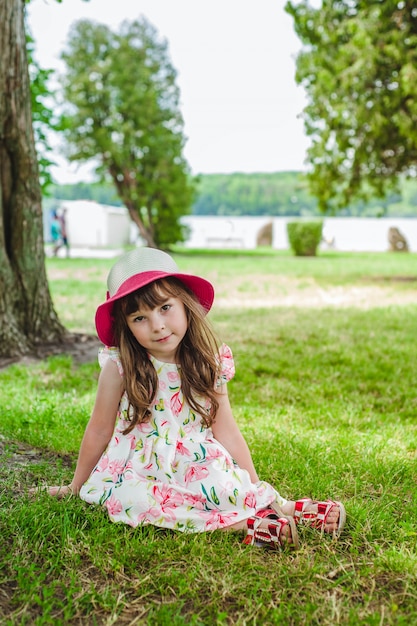 Bambina seduta sul prato di un parco