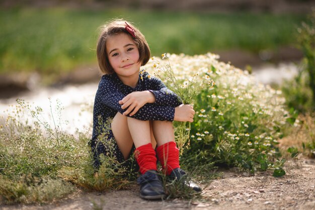 Маленькая девочка, сидя в природе поле носить красивые платья