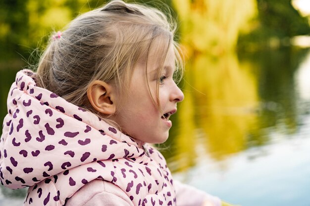 Little girl sitting in park near the lake