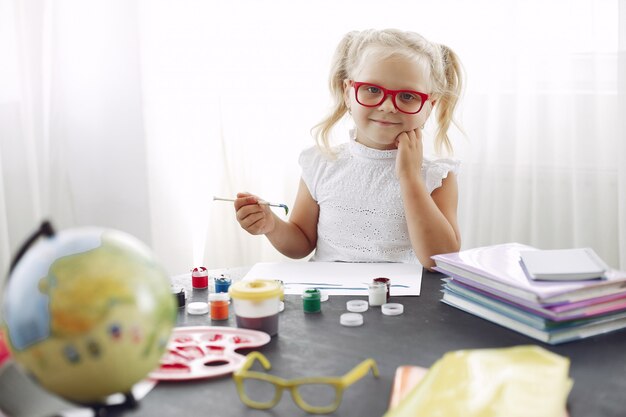 Little girl sitting on a table and drawing