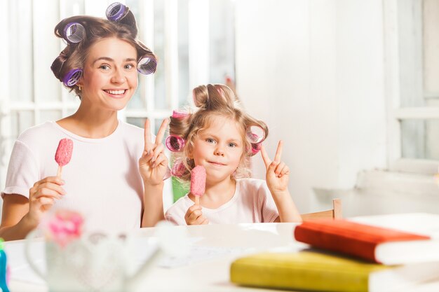 彼女の母親と一緒に座ってアイスクリームを食べる少女