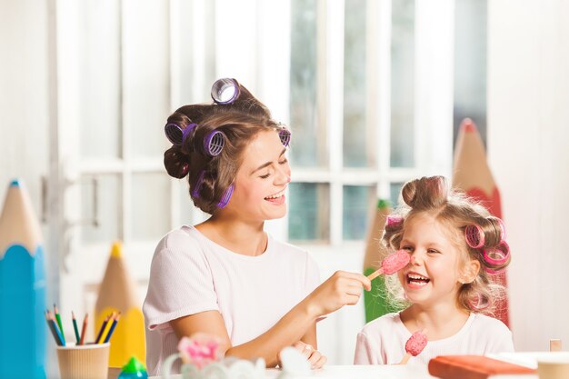 Little girl sitting with her mother and eating ice cream