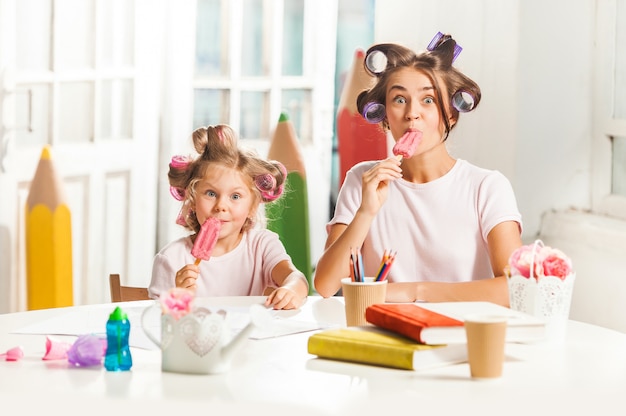 彼女の母親と一緒に座っているとアイスクリームを食べる少女