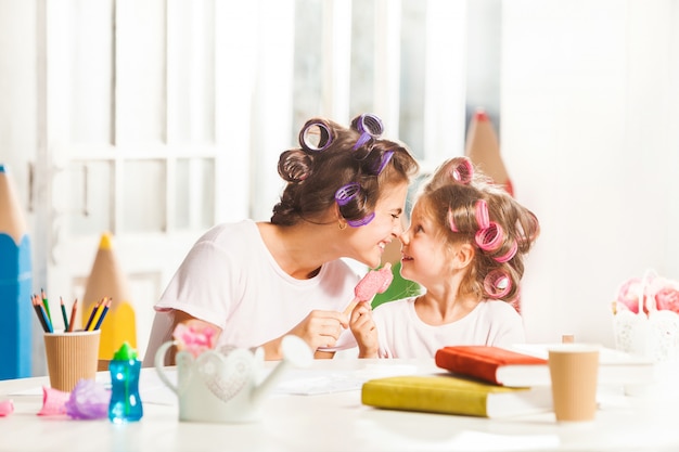 彼女の母親と一緒に座っているとアイスクリームを食べる少女