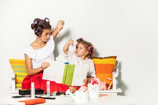 Little girl sitting with her mother and looking at a photo album