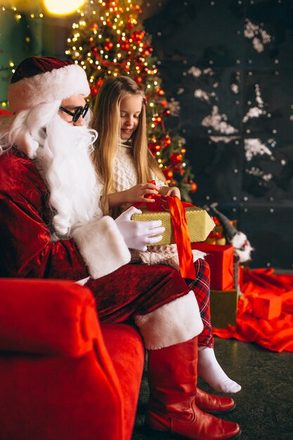 Little girl sitting with santa and presents on Christmas