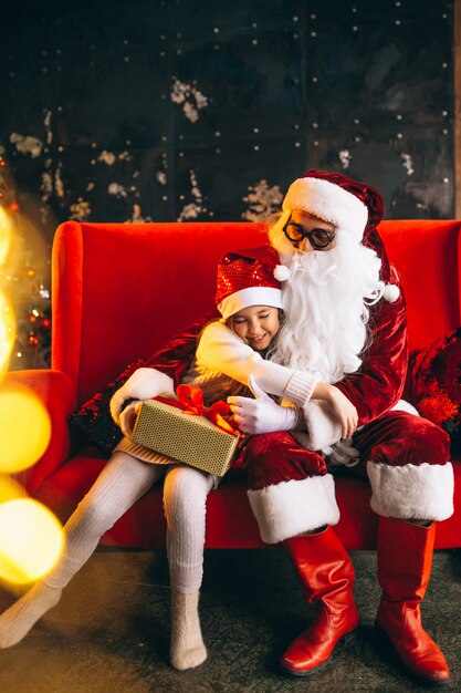 Little girl sitting with santa and presents on Christmas