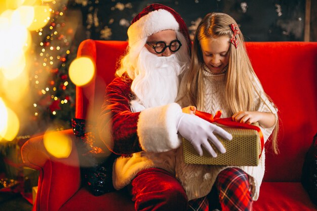 Little girl sitting with santa and presents on Christmas