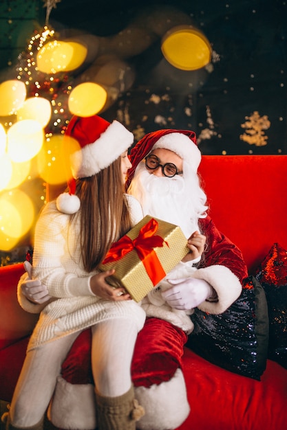 Bambina che si siede con santa e regali a natale