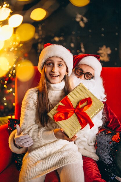 Little girl sitting with santa and presents on christmas