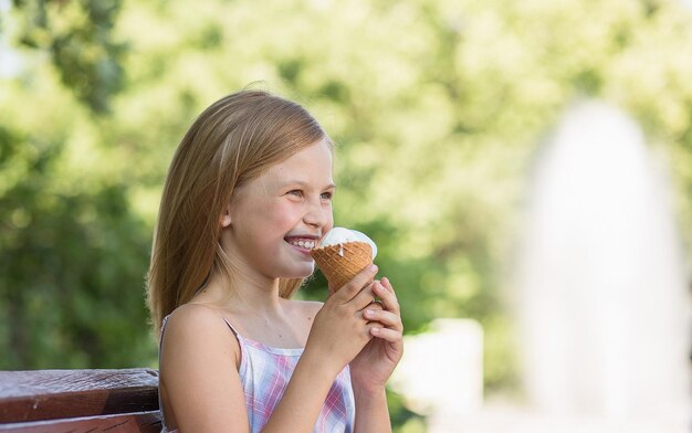 Маленькая девочка улыбается, держа мороженое