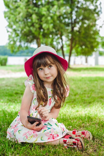 Маленькая девочка, улыбаясь с помощью смарт-телефона