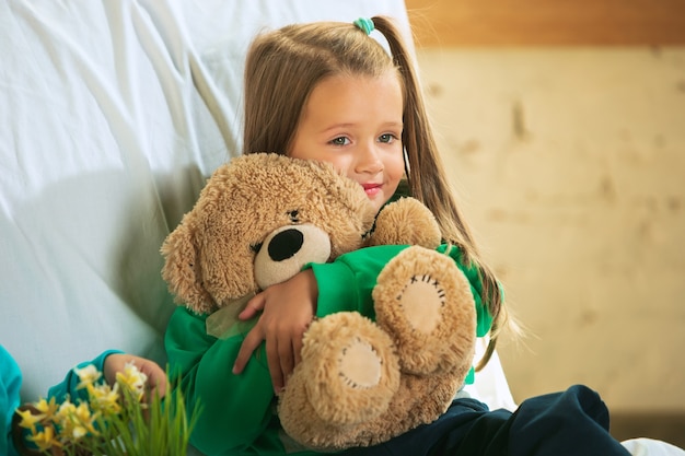 Little girl in soft warm pajama playing at home.