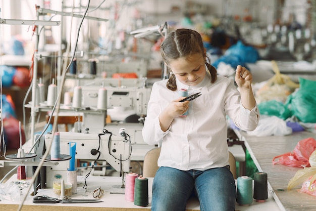 Little girl standing in the factory with a thread